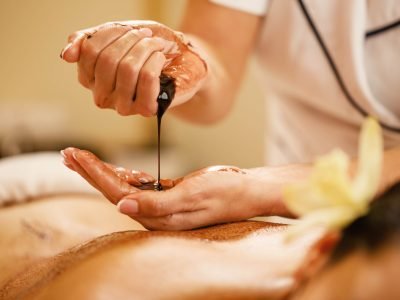 closeup-massage-therapist-pouring-hot-chocolate-her-hands-before-spa-treatment-min